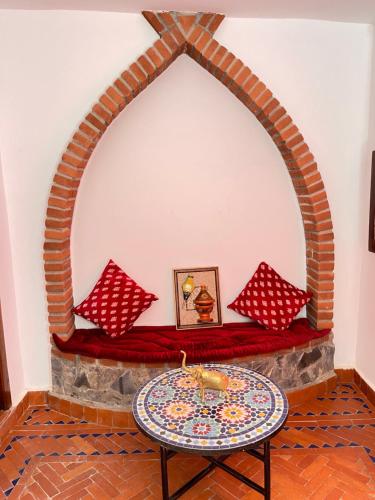 a living room with a stone fireplace with a table at Riad Bab Mahrouk in Chefchaouene