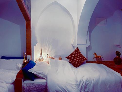 a bedroom with two beds and an arched window at Riad Bab Mahrouk in Chefchaouene