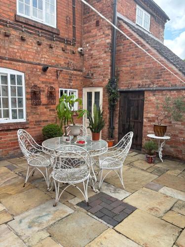 a patio with a table and chairs in front of a brick building at Crabapple Cottage adult only in Castle Donington