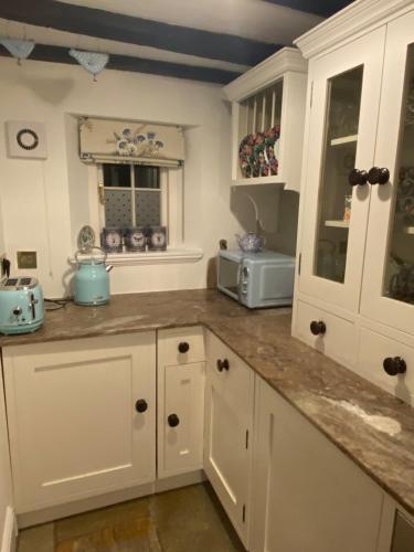a kitchen with white cabinets and a counter top at Crabapple Cottage adult only in Castle Donington