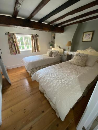 two beds in a room with wooden floors and a window at Crabapple Cottage adult only in Castle Donington