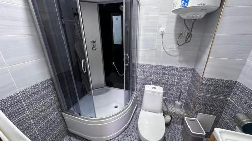a bathroom with a toilet and a glass shower at УЮТ отель и хостел in Jalal-Abad