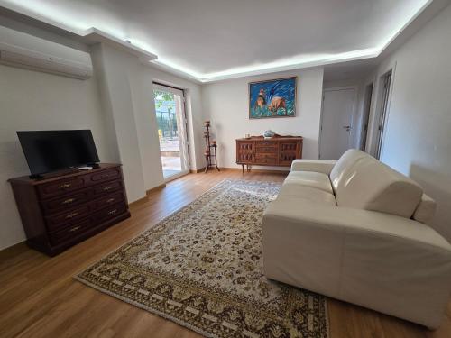 a living room with a white couch and a tv at A Casa das Tias in Benedita