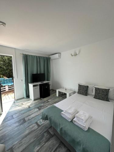a bedroom with a white bed and a television at VILA ONEIRO in Vama Veche