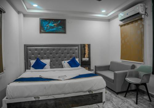 a bedroom with a large bed and a chair at Hotel Vayuputra Grand in Secunderabad