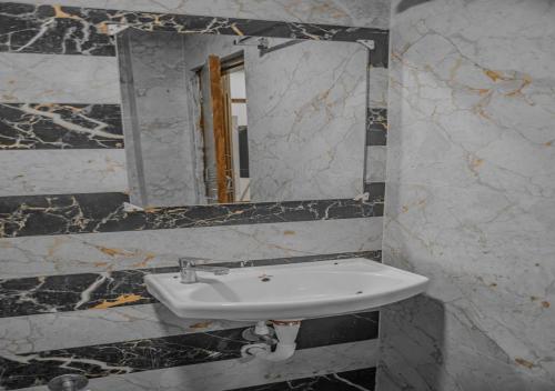 a bathroom with a sink and a mirror at Hotel Vayuputra Grand in Secunderabad