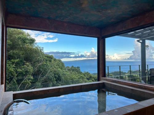 a bath tub with a view of the ocean at グラン熱川 in Higashiizu