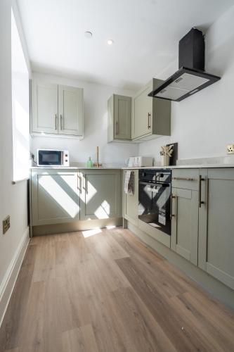 a kitchen with white cabinets and wooden floors at Flat 9- 1BR in Newport