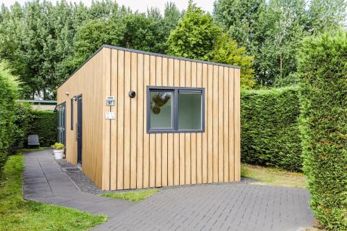 a small wooden shed with a window on a sidewalk at Stijlvol Tiny House Zeeland - Centraal gelegen VP022 in Heinkensand
