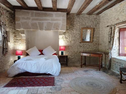 une chambre avec un lit et une table dans une pièce dans l'établissement Chambre dans tour du 15ème siècle, à Mauvières