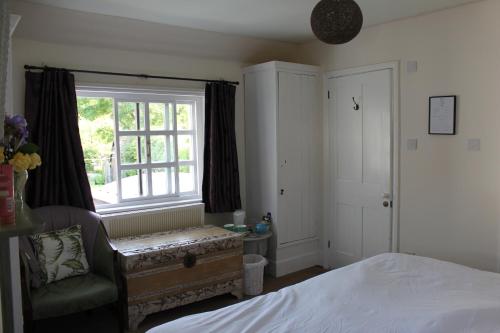a bedroom with a bed and a window and a chair at B&B South Downs Way in Poynings