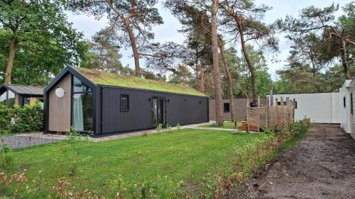 a black house with a grass roof at Snoozz retreats in Haarle