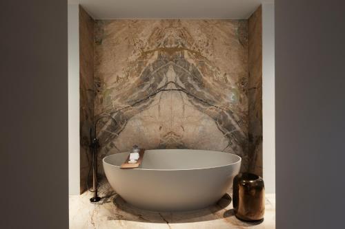 a bath tub in a bathroom with a stone wall at Rosewood Amsterdam in Amsterdam