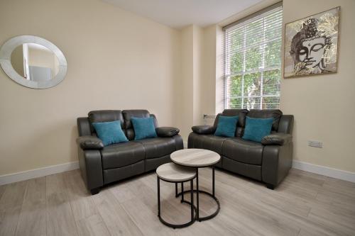 a living room with two leather couches and a table at Warwick Row Apartments Coventry City Centre - Flat 1 in Coventry