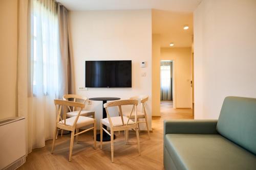 a living room with a table and chairs and a tv at Toplice Family Inn - Terme Čatež in Čatež ob Savi