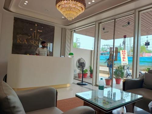 a woman standing behind a counter in a room with a table at Hotel K A Square in Bhopal