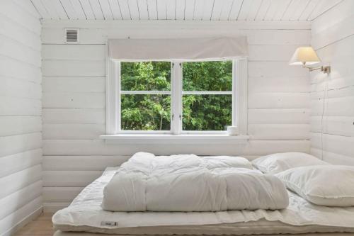 a white bedroom with a bed and a window at Log House In Dronningmølle, 150 M To The Beach in Dronningmølle