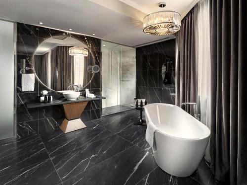 a bathroom with a tub and a large mirror at Mamaison Hotel Chain Bridge Budapest in Budapest