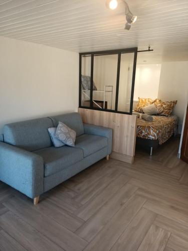 a living room with a blue couch and a mirror at Escapade cosy à Voglans avec terrasse au calme in Voglans