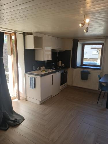 a small kitchen with white cabinets and a window at Escapade cosy à Voglans avec terrasse au calme in Voglans