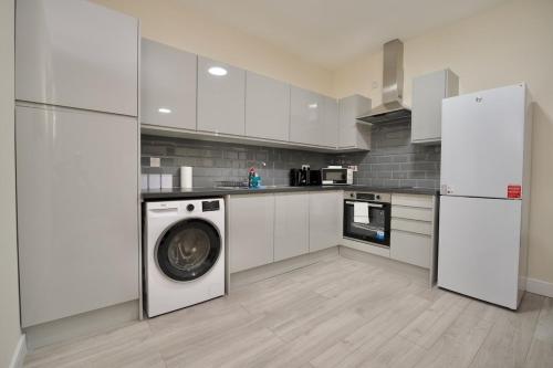 a kitchen with white cabinets and a washer and dryer at Warwick Row Apartments Coventry City Centre - Flat 2 in Coventry