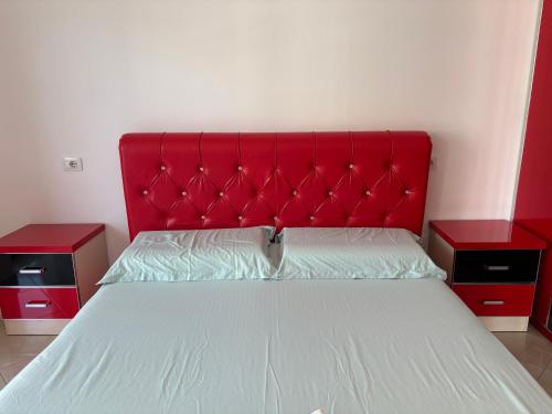 a bed with a red headboard and two night stands at Chloe Beach Apartment in Lezhë