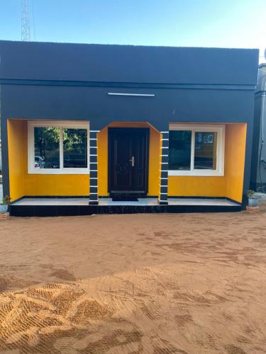 a blue and yellow building with a black door at Ramachi Apartment A in Livingstone