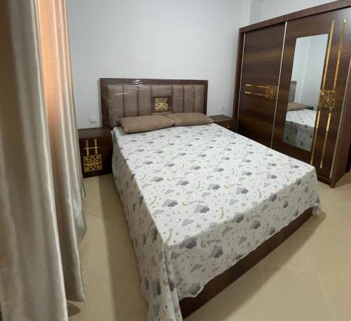 a bedroom with a bed with a dresser and a mirror at Appartement À Martil in Martil