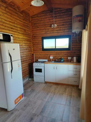 a kitchen with a white refrigerator and a window at Campo Cuyen, Cabañas in Lobos