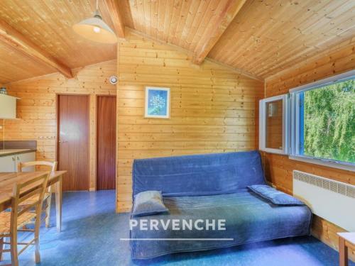 a room with a blue couch in a wooden cabin at Gîte des fleurs - 5 Chalets in Saint-Prix