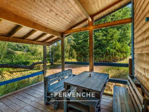 a wooden porch with a wooden bench and a table at Gîte des fleurs - 5 Chalets in Saint-Prix
