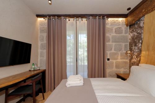 a bedroom with a bed and a desk and a television at Planinarski dom Vošac in Makarska