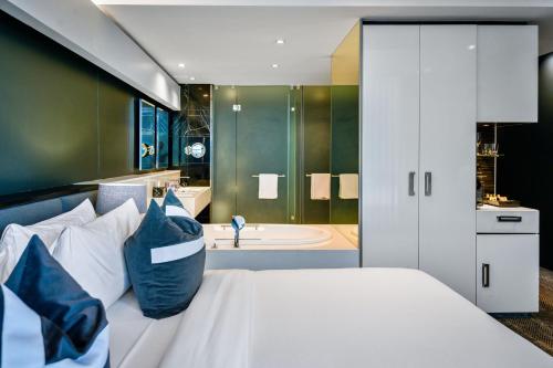 a bedroom with a bed and a bathroom with a tub at The Capital 15 on Orange Hotel & Spa in Cape Town