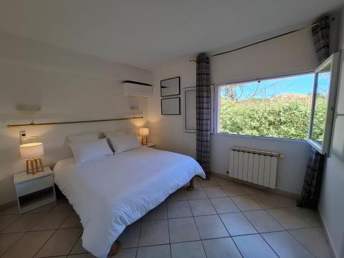 une chambre avec un lit blanc et une grande fenêtre dans l'établissement Villa Sylvana in Provence-Huge Garden, AC and Terrace, à Gonfaron