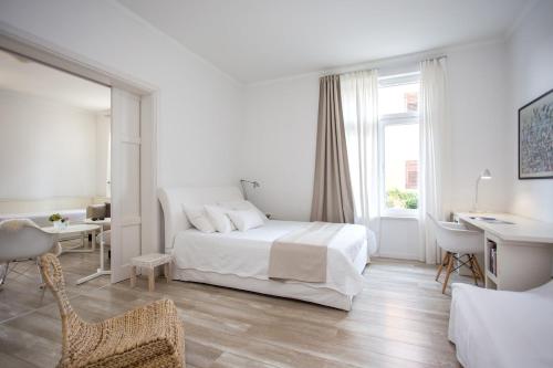 a white bedroom with a bed and a desk and a window at Villa Rotondo-charming villa few steps from beach in Kaštela