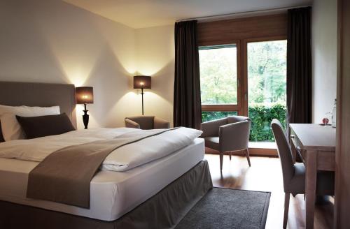 a bedroom with a bed and a desk and a window at Hotel Schloss Hünigen in Konolfingen