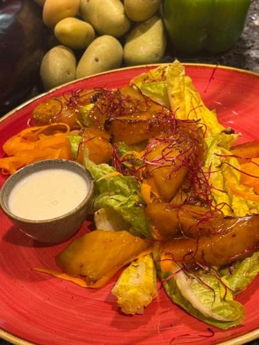 a red plate of food with a salad and sauce at Holiday Inn Lübeck by IHG in Lübeck