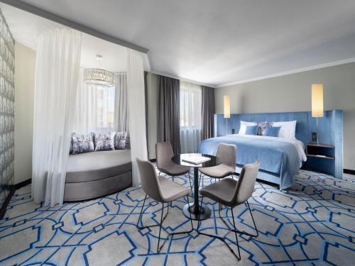 a hotel room with a bed and a table and chairs at Mamaison Hotel Chain Bridge Budapest in Budapest