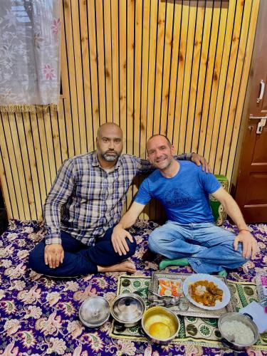 two men are sitting on a blanket with food at Sea Green Guest House in Srinagar