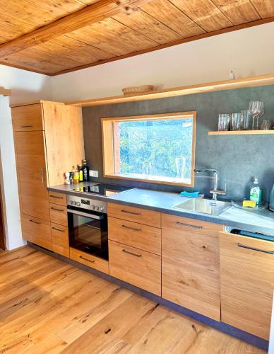 a kitchen with wooden cabinets and a sink and a window at Das Alpl Resort in Krieglach