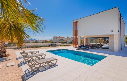 a villa with a swimming pool and two lounge chairs at Lovely Home In Vodice in Vodice