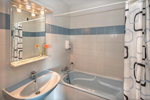 y baño con bañera y lavamanos. en Hôtel-Restaurant Le Calice Du Gevaudan - A75, en Banassac