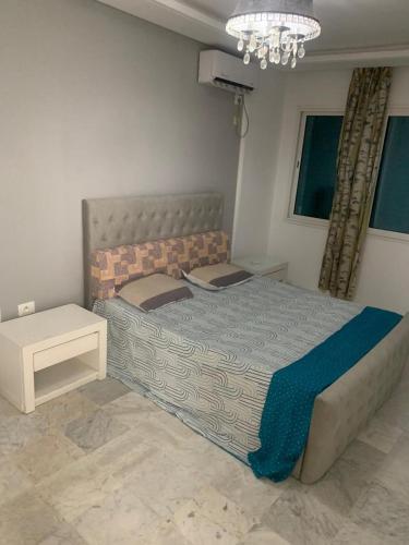 a bedroom with a large bed and a chandelier at Studio deux pas à la plage in Hammam Sousse