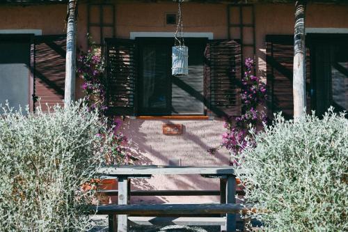 a wooden bench in front of a house with flowers at Agriturismo Vallerana in Capalbio