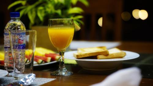 a glass of orange juice next to a plate of toast at The Nature Resort in Dambulla
