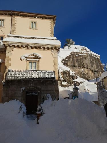 a building covered in snow next to a mountain at Charming apartment Pescocostanzo in Pescocostanzo