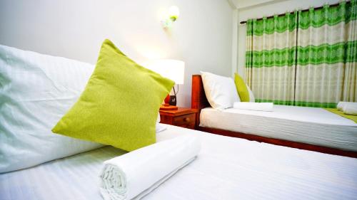 a hotel room with two beds with green and white pillows at The Nature Resort in Dambulla