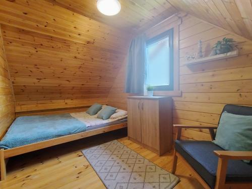 a room with a bed in a wooden cabin at Domki Bursztynowa Zatoka 2 in Sarbinowo