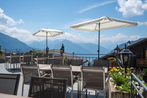 a restaurant with tables and umbrellas and a view of the mountains at Hotel Aletsch in Bettmeralp