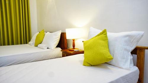 two beds with yellow and white pillows in a room at The Nature Resort in Dambulla